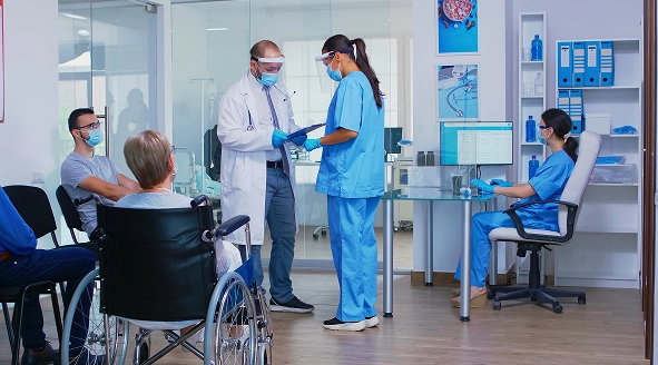 Personal médico de Acemi en consultorio atendiendo a pacientes y revisando expedientes clínicos en una sala de espera moderna.